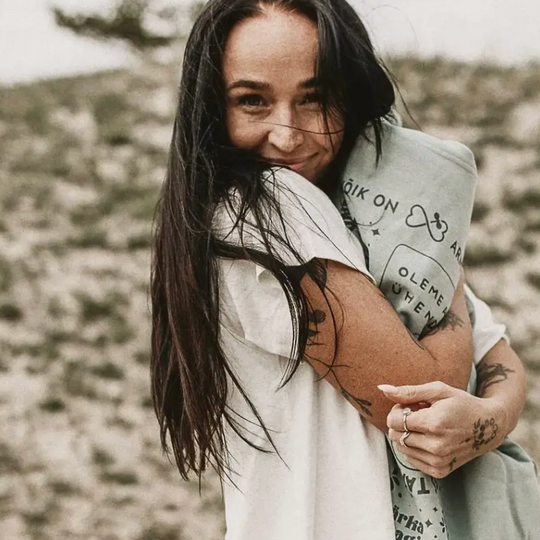 A smiling woman outdoors with her arms folded.