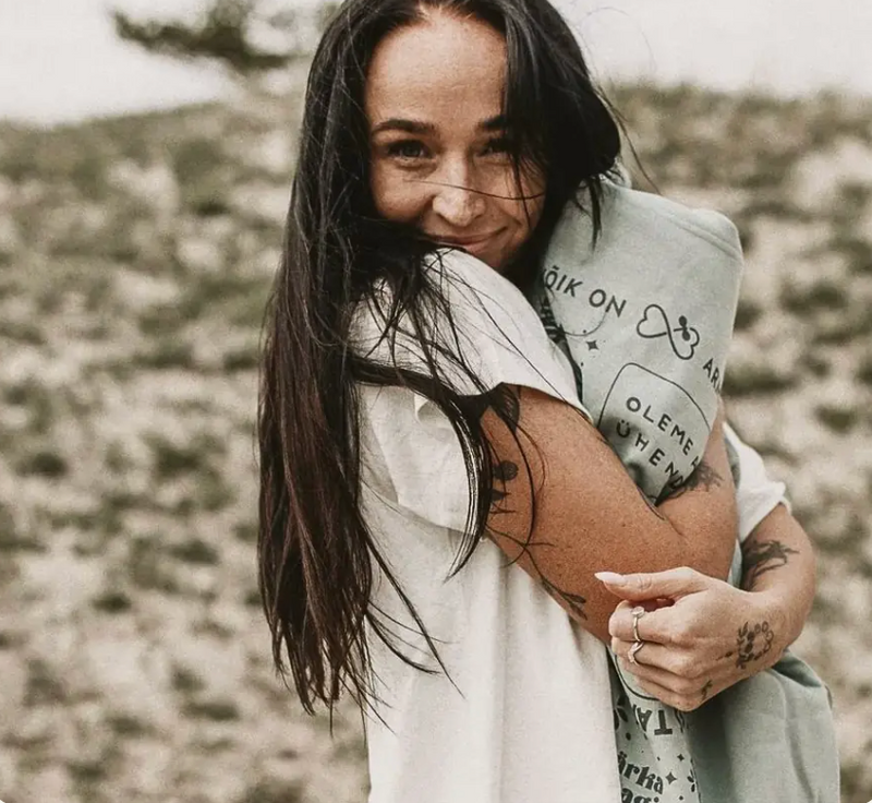 A smiling woman outdoors with her arms folded.