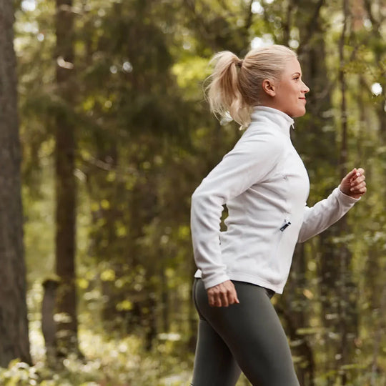 A woman running along a woodland trail.