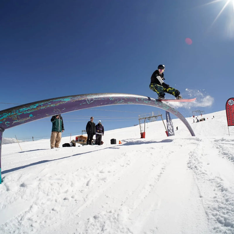 A snowboarder in the air above a snowy mountain slope.